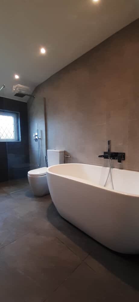 Bathtub, water closet and a separate shower area near the window - Bromley bathrooms by Jikka