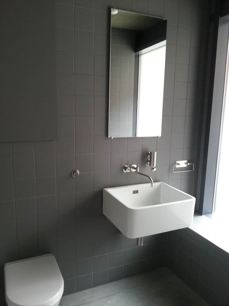 Bathroom design with a wall mounted water closet and a wahsbasin near the window by Jikka